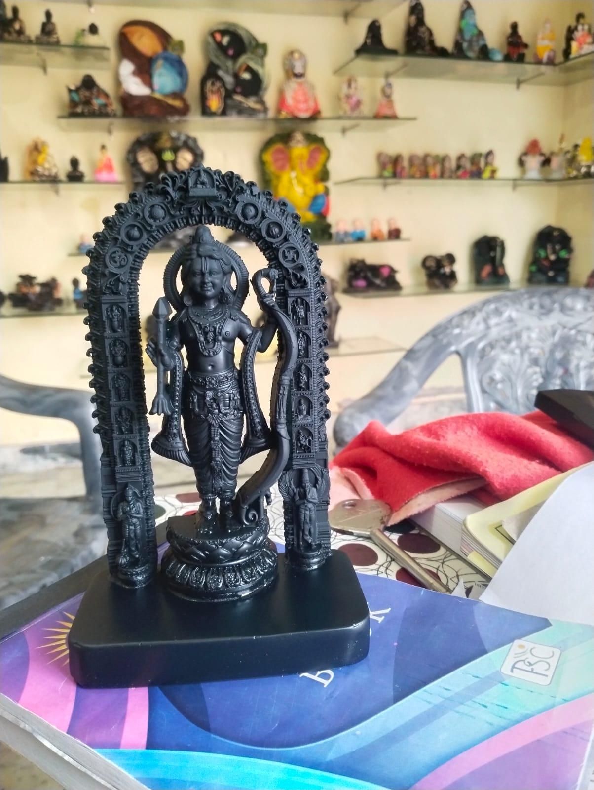 Black statue of a deity with an arch on a colorful surface, with shelves of similar statues in the background.